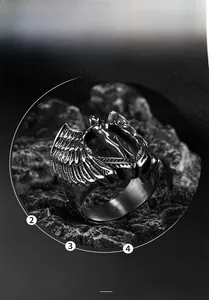 Macro shot of stainless steel winged ring with central figure on dark stone