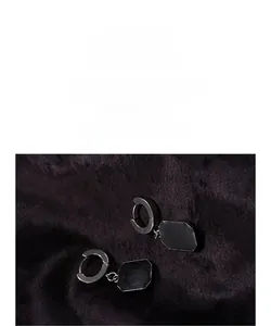 Detail of minimalist silver hoop earrings featuring black octagonal geometric pendants