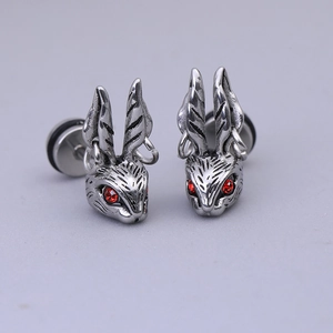 Détail des boucles d'oreilles lapin vintage avec yeux rouges et textures métalliques