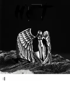 Detailed close-up of retro silver angel wing steel ring on black rock surface