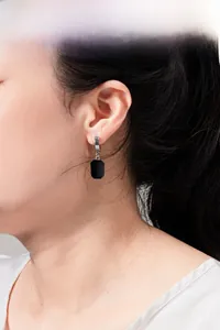 Close-up of minimalist black rectangular drop earrings with polished silver metal hooks