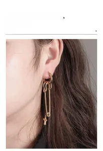 Close-up of gold safety pin earrings with cross pendant on a model in vintage style