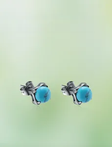 Macro detail of turquoise stud earrings with silver metal backing and natural stone texture