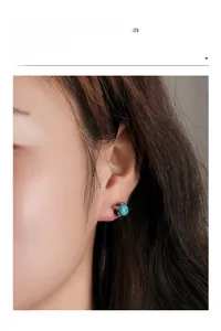 Close-up of a model wearing a green turquoise stud earring with silver six-prong setting