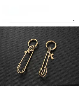 Detail of gold safety pin earrings with small cross charms on a textured display