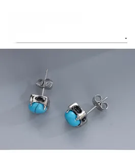 Detailed close-up of turquoise stud earrings with vintage silver claw setting and butterfly backs