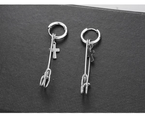 Detail view of silver punk safety pin earrings with cross charms on black background
