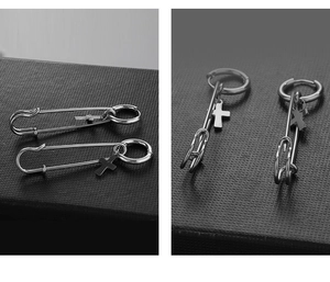 Detailed view of silver stainless steel safety pin and cross charm earring on stand