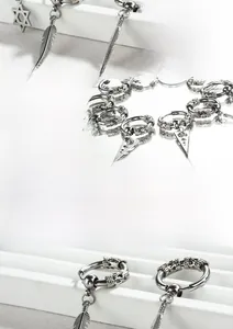 Détail de boucles d'oreilles en acier inoxydable poli avec breloques croix et dragon