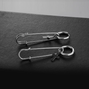 Punk silver stainless steel safety pin earrings with cross charms on a black display