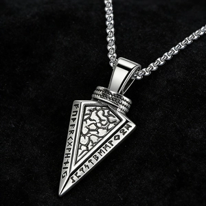 Macro detail of silver Viking arrowhead pendant with Runic symbols and rock texture
