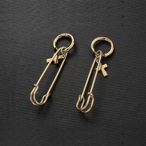 Minimalist gold stainless steel safety pin earrings with small cross charms on black background