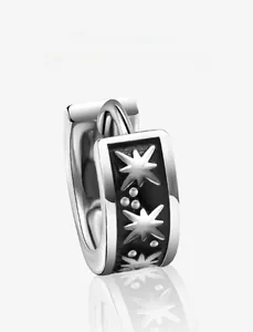 Detail of square titanium steel earrings with embossed star patterns and black finish