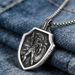 Detail of vintage shield pendant featuring a Spartan warrior relief on blue denim