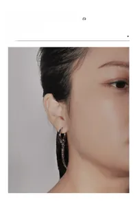 Close-up of minimalist stainless steel cross drop earring worn on model's ear