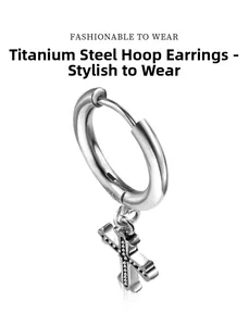 Detail of silver titanium steel hoop earring featuring a textured cross pendant