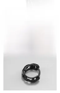 Macro view of matte black stainless steel huggie earrings with intricate engraved patterns