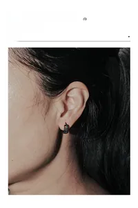Close-up of minimalist black patterned stainless steel hoop earring worn on model