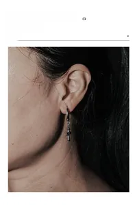Macro shot of silver stainless steel cross hoop earring on model with dramatic lighting