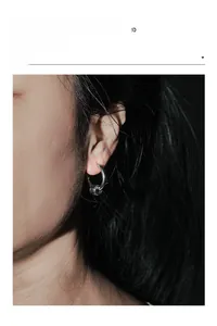 Close-up of minimalist silver hoop earring with textured bead on a model