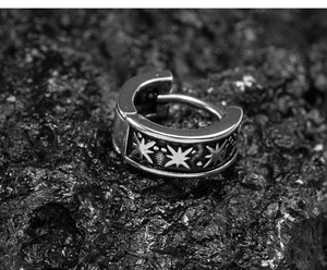 Detailed macro view of square stainless steel earring with engraved star patterns on rock