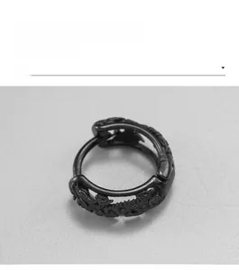 Macro shot of black stainless steel hoop earring with detailed dragon motif engraving