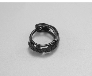 Macro shot of black stainless steel huggie earring with gothic dragon scale engraving
