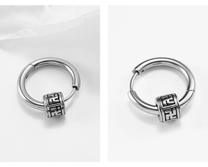 Detail of silver stainless steel hoop earrings with rotating engraved cross charm