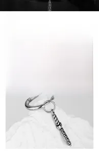 Macro shot of silver stainless steel earring featuring a textured cone pendant in punk style