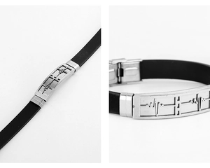 Detail of black silicone bracelet with engraved heartbeat pattern on silver steel plate