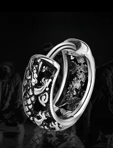 Gros plan de boucles d'oreilles en acier argenté hip hop avec des reliefs d'écailles de dragon