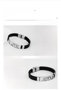 Dettaglio macro della placca in acciaio lucido 'Love' su un bracciale in silicone nero