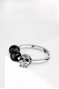 Détail de la boucle d'oreille gothique en acier avec perles noires et tête de mort