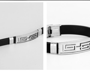 Detail of men's stainless steel bracelet featuring Greek Key pattern and black rubber strap