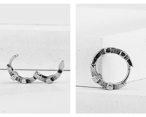 Detail of vintage punk style hinged hoop earrings with textured finish and buckle design