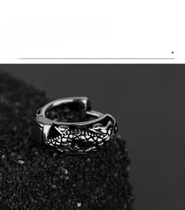 Détail des boucles d'oreilles relief dragon en argent vieilli sur une pierre noire mate