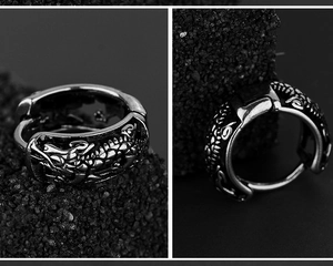 Détail macro d'une boucle d'oreille en acier avec relief dragon et finition oxydée
