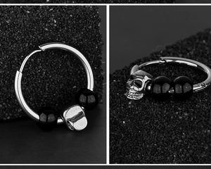 Détail macro du pendentif crâne punk avec perles noires sur boucle d'oreille en acier titane