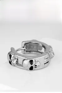 Dettaglio macro di orecchini a teschio in argento dallo stile punk e vintage