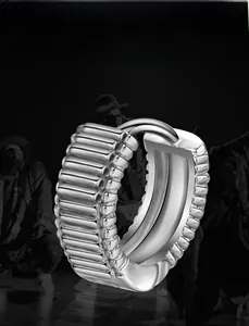 Détail d'une boucle d'oreille à charnière argentée avec texture rainurée hip-hop