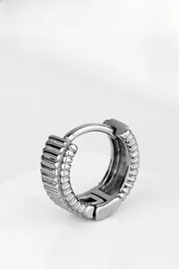 Détails macro d'une boucle d'oreille argentée avec rayures verticales et bords perlés