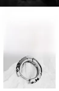 Gros plan de boucles d'oreilles rétro en acier titane mat avec motifs étoiles gravés