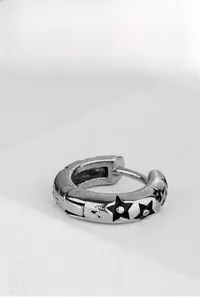 Vue macro de boucles d'oreilles argentées vintage avec trois motifs pentagramme noirs