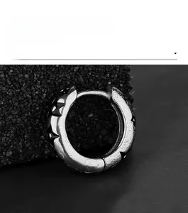Gros plan d'une boucle d'oreille huggie argentée avec gravures d'étoiles noires sur pierre