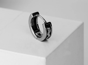 Macro view of matte stainless steel huggie earring with black geometric sawtooth engraving