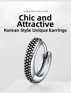 Detail of silver stainless steel hoop earring with black dotted industrial texture