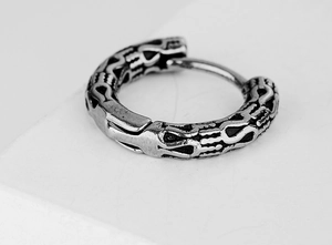Macro shot of silver hinged earring with black relief texture and industrial aesthetic