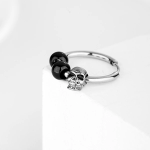 Boucles d'oreilles créoles tête de mort en acier avec perles noires sur socle blanc