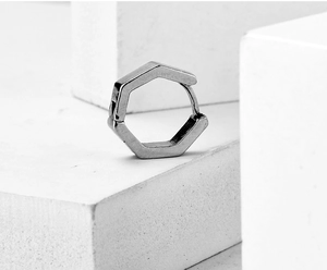 Detailaufnahme des sechseckigen silbernen Edelstahl-Ohrrings auf geometrischen Blöcken