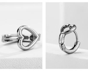 Macro detail of vintage silver heart-shaped stainless steel hoop earrings on stone